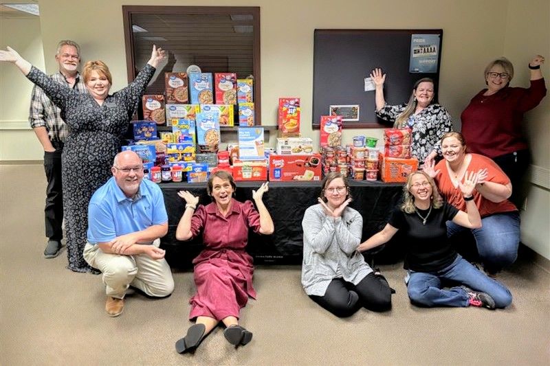People sitting and standing around a table of food.
