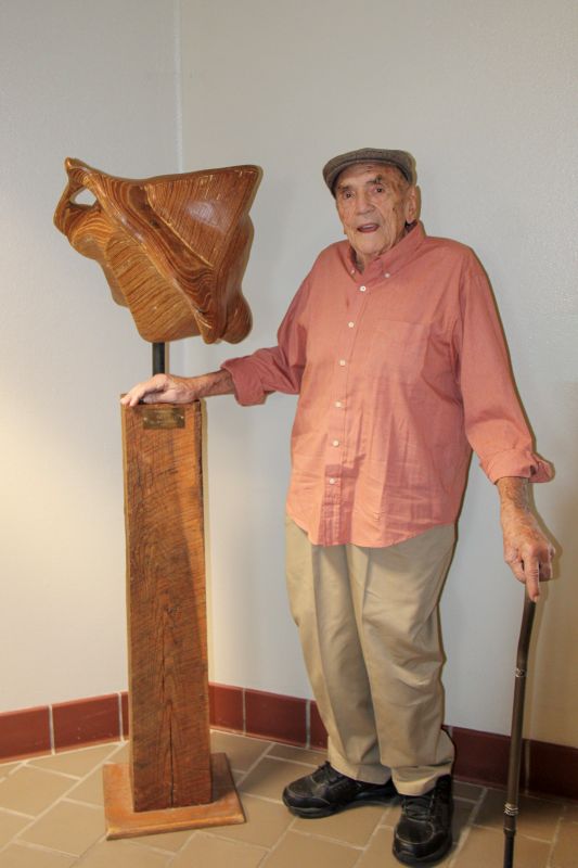 Marvin Hester standing with his wooden art piece.