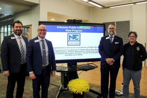 Four people standing around a tv monitor.