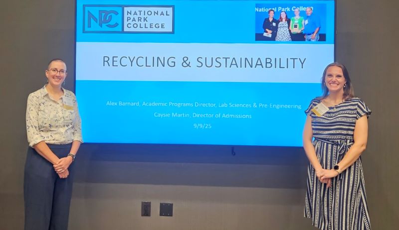 two women standing in front of a drop down screen.
