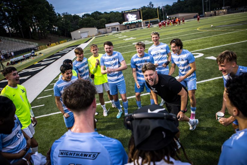 Men's soccer group and coach celebrating.