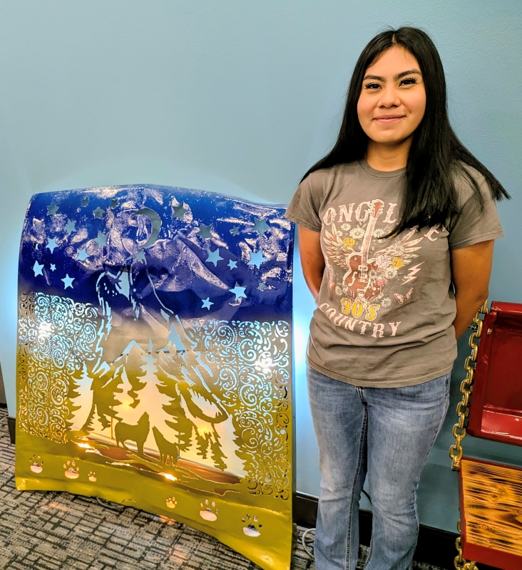 Arismel Nestor stands beside the car hood she welded.