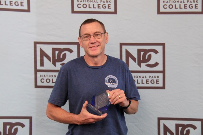 Jason Armitage holding the 2026 NPC Outstanding Faculty Member award.