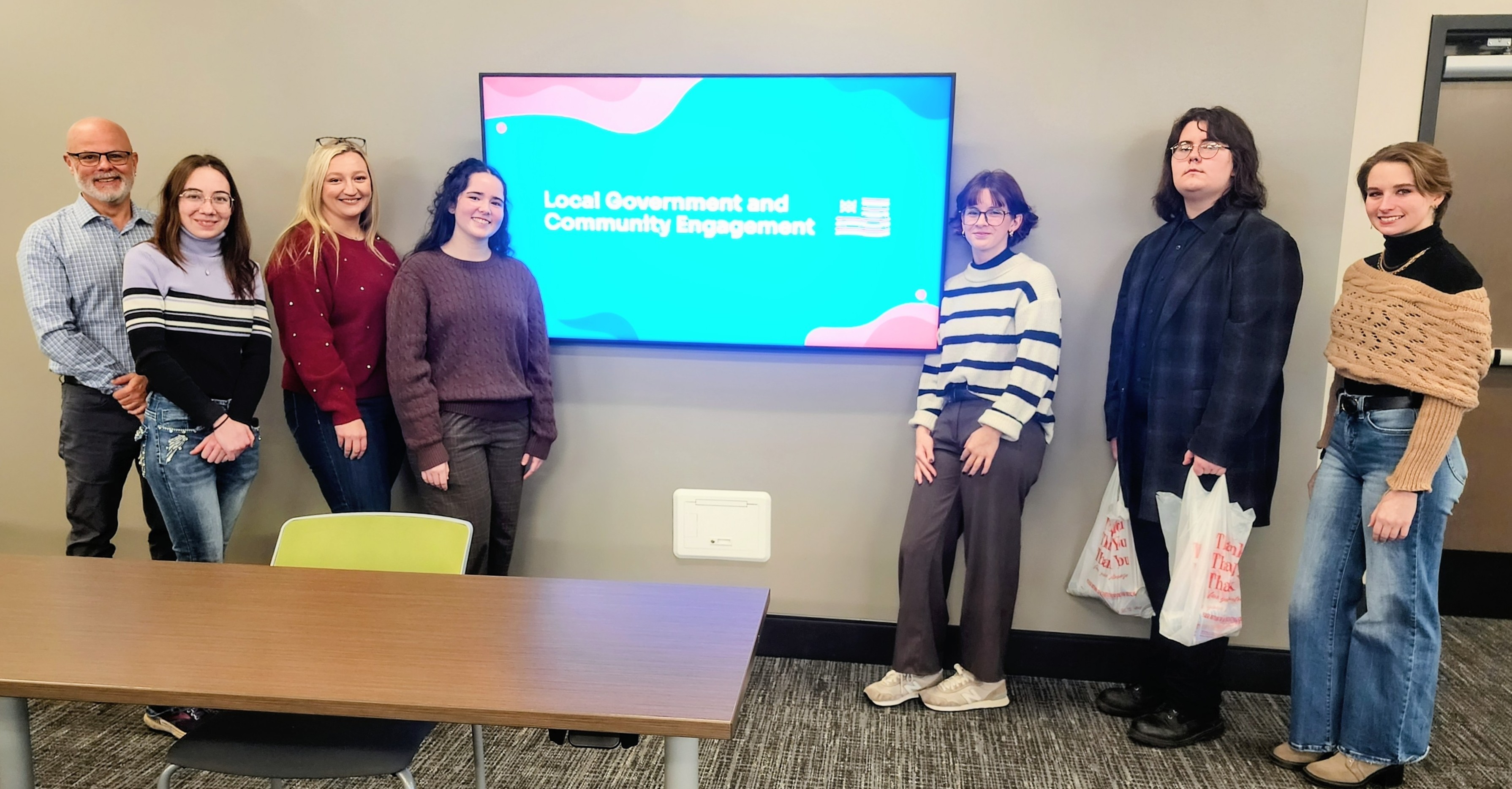 People posing in front of a tv screen.
