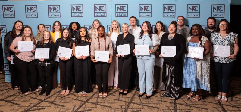 A group of students holding certificates in front of banners that say NPC. 