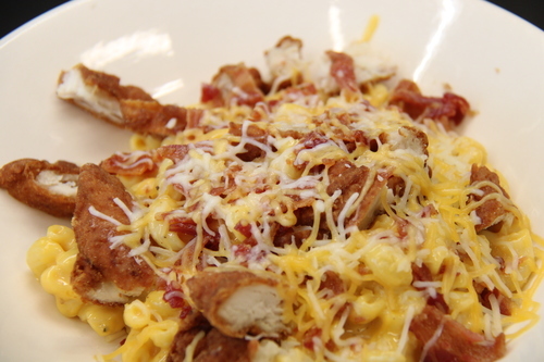 mac and cheese with fried chicken and shredded cheese in a bowl