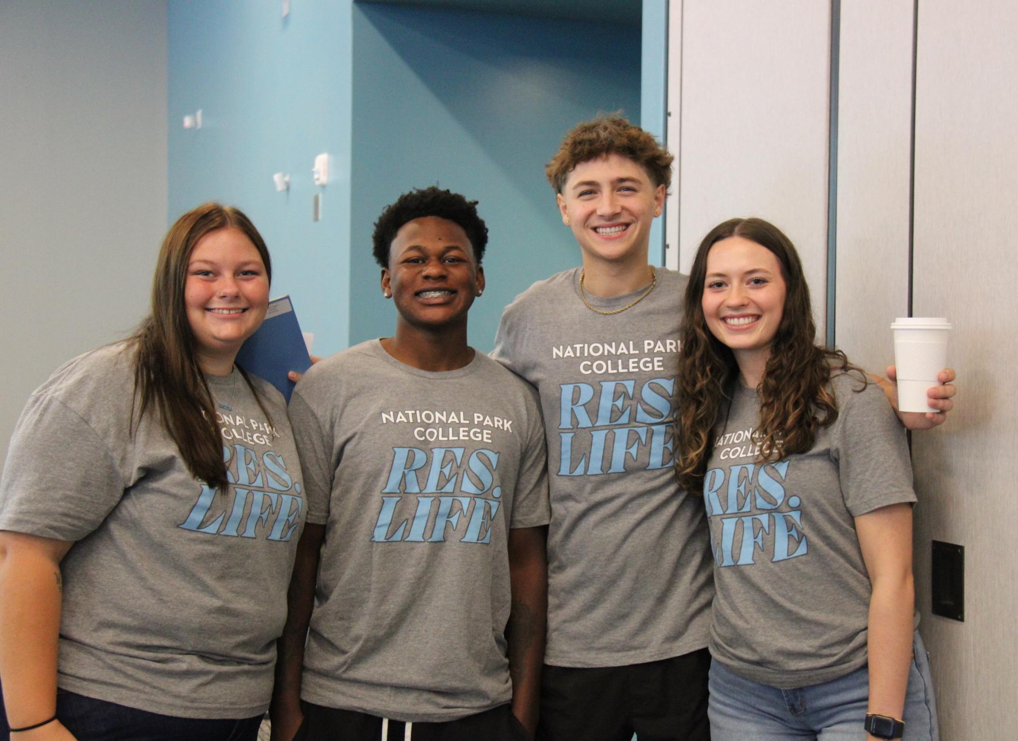 Four students wearing matching RESLIFE shirts posing for a picture